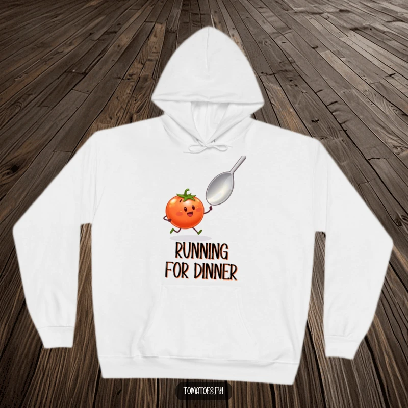 Funny hoodie depicting a tomato character with tiny legs sprinting towards a giant spoon, cozy and comedic food chase apparel.